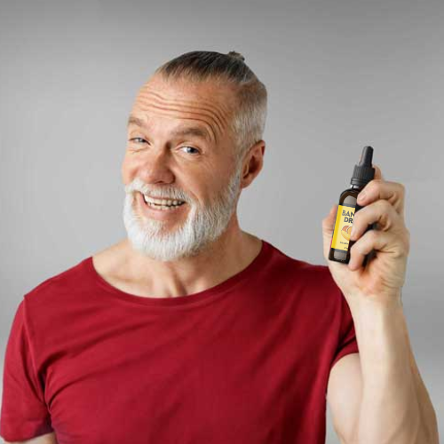 Man in red shirt and with beard holding a bottle of Banana Drops